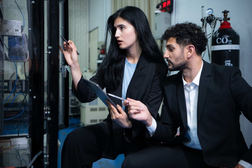 Woman and man cybersecurity workers pointing out a possible error.