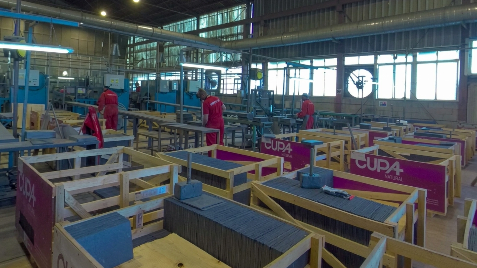 Operarios de Cupa Pizarras clasificando y embalando pizarra natural en palés dentro de la nave
