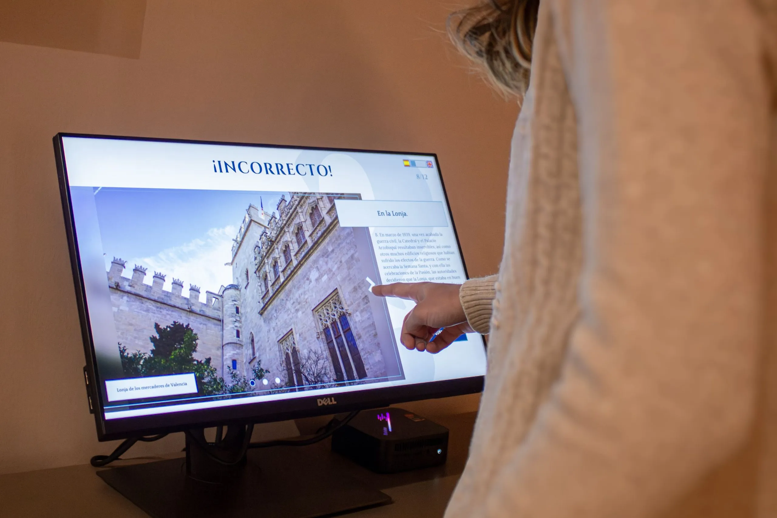 Una usuaria interactúa con una pantalla táctil que muestra el mensaje "¿INCORRECTO!", parte de un quiz o juego educativo sobre la historia del Santo Cáliz